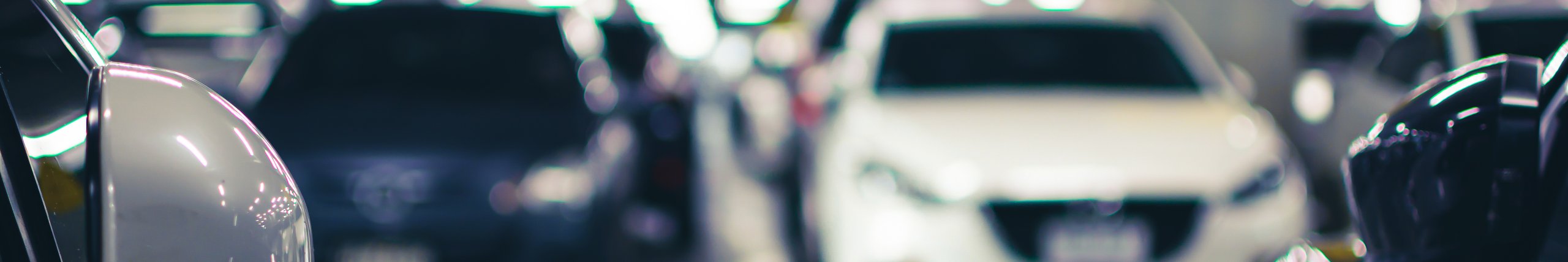 Moderne og veloplyst parkeringsplads med parkerede biler.